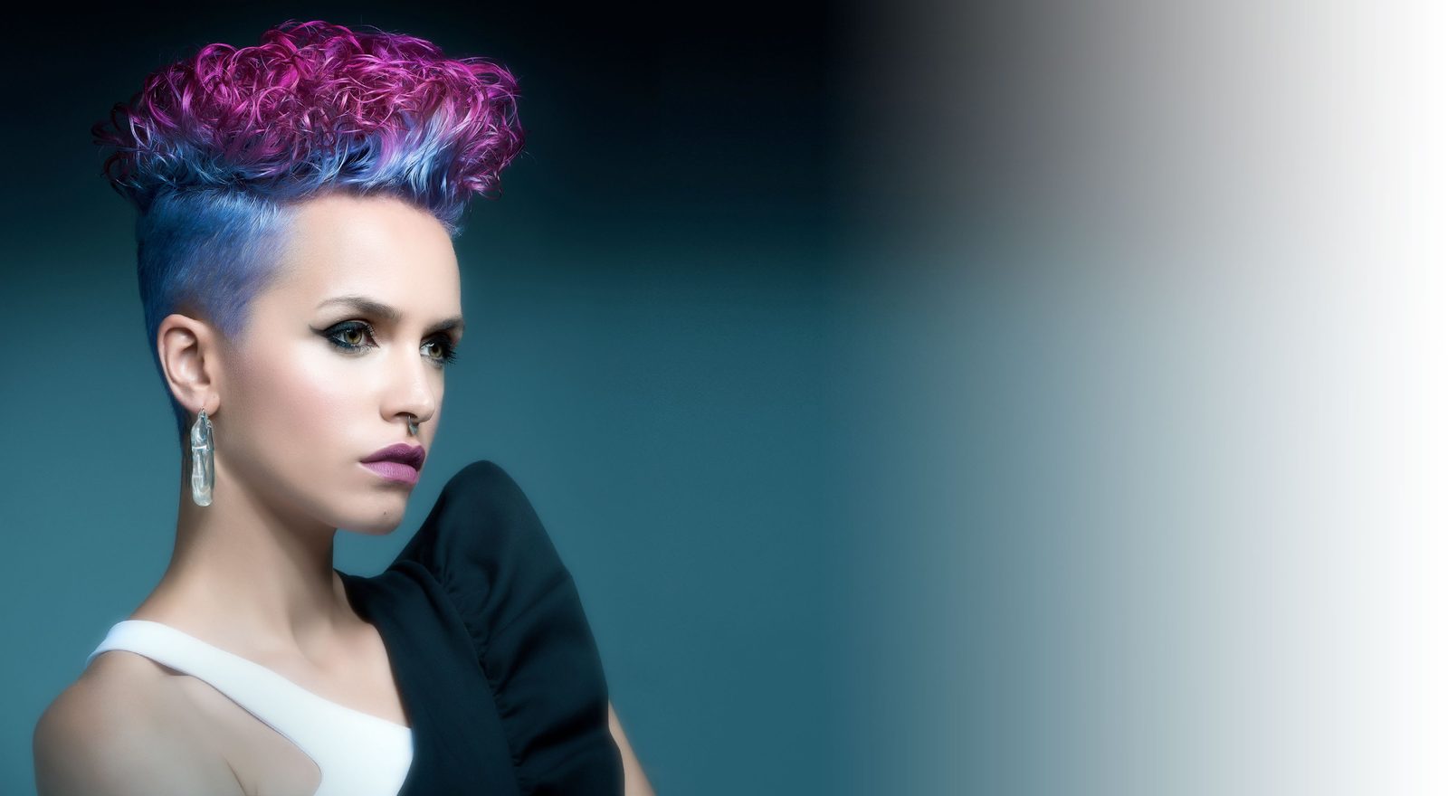 Modella con capelli corti colorati in viola e blu su fondo petrolio
